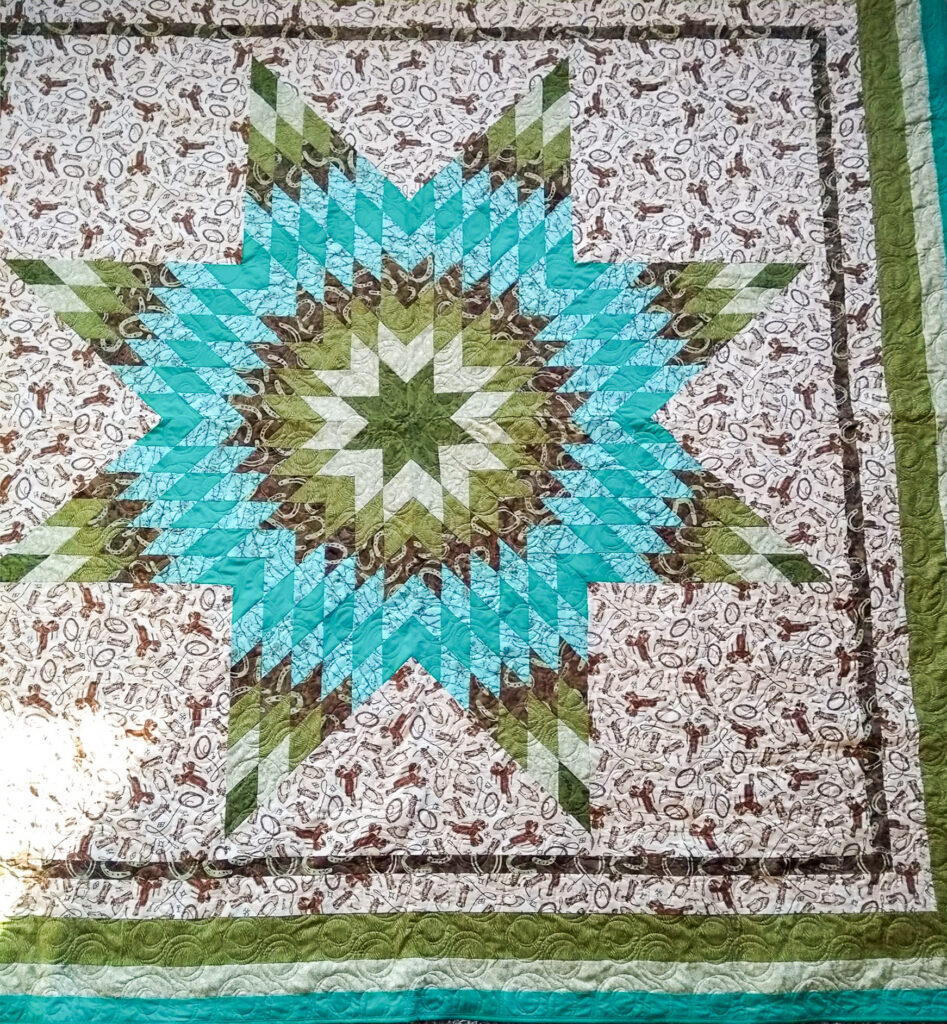 A quilt made of greens, blues, and beige patterned fabrics. It is made as a star quilt, with pieces depicting an eight-point star.