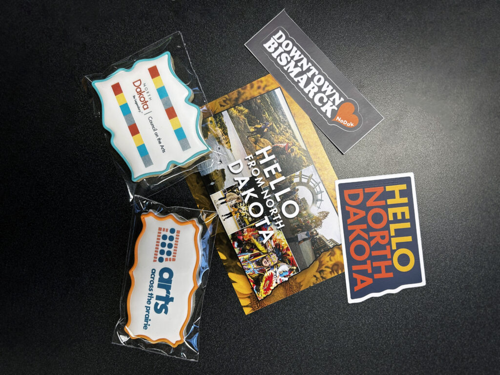 An assortment of five nametags, stickers, and postcards from North Dakota