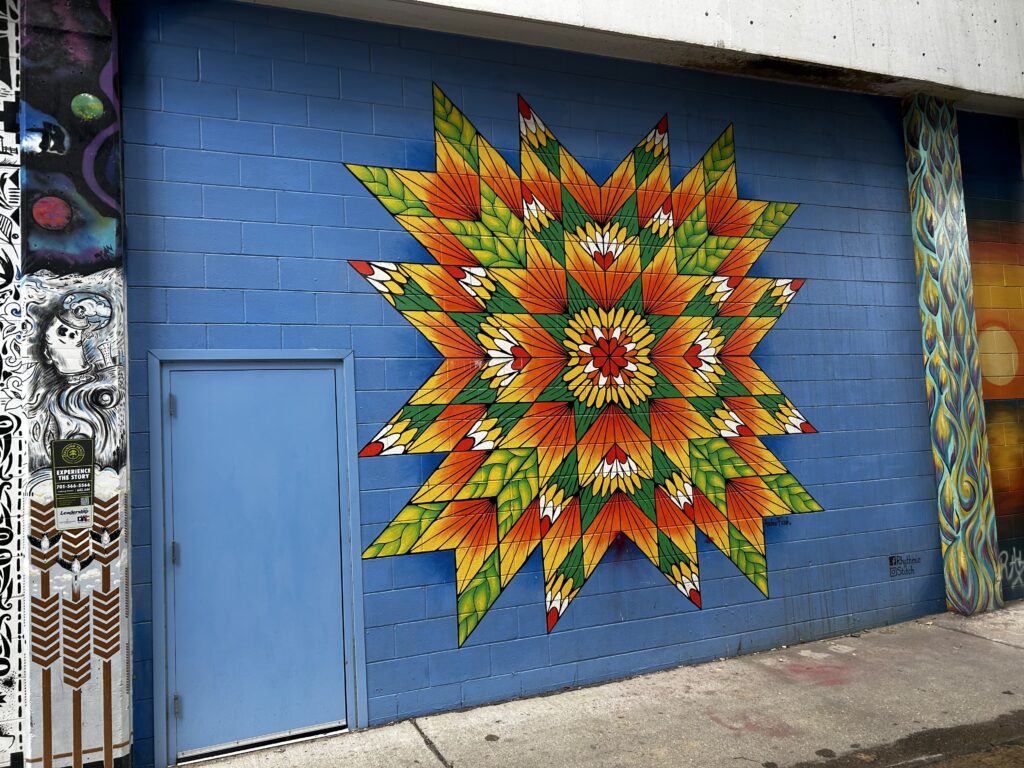 A mural of a star quilt on a blue background