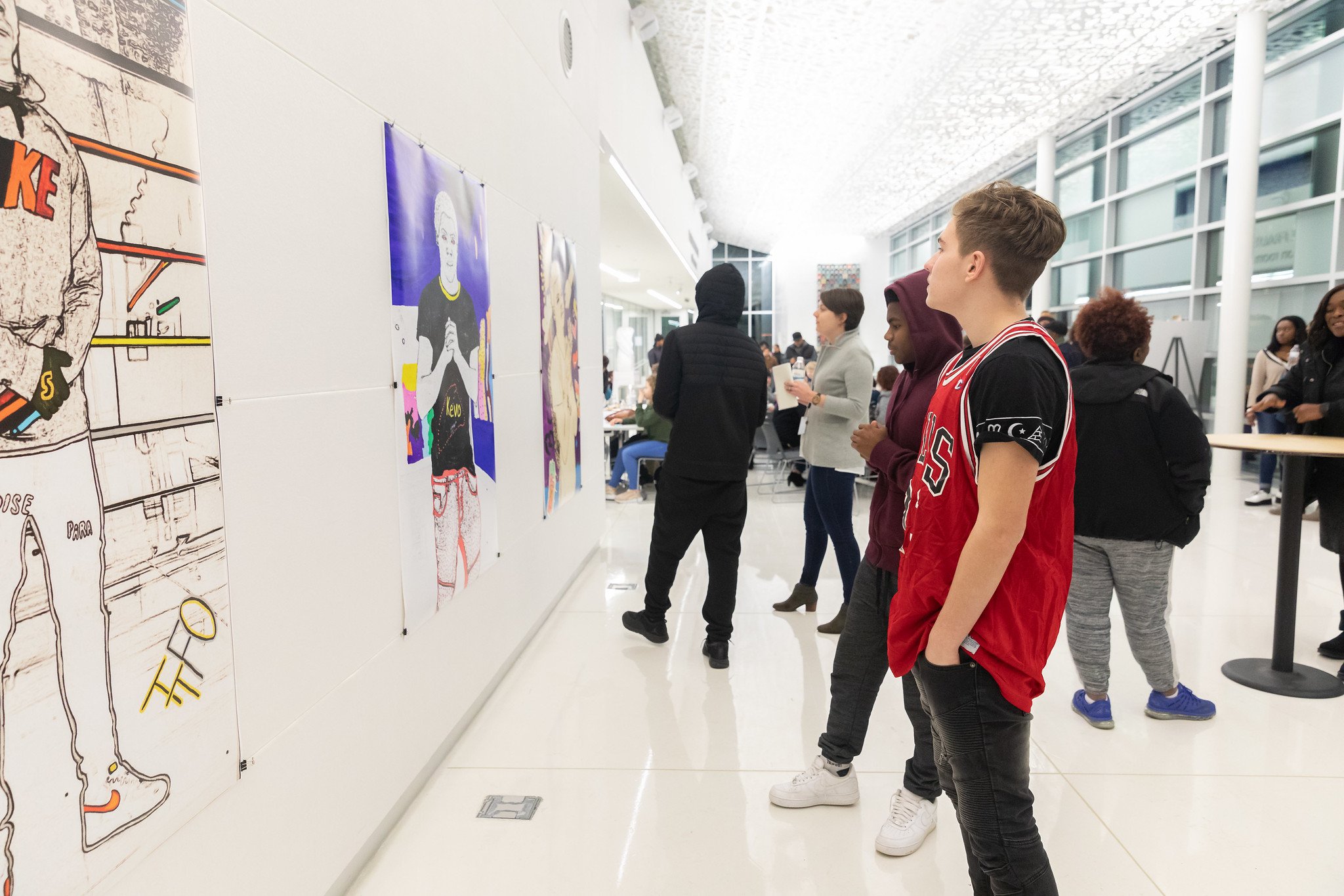 A teen in a basketball jersey looks at a piece of art in a gallery show.
