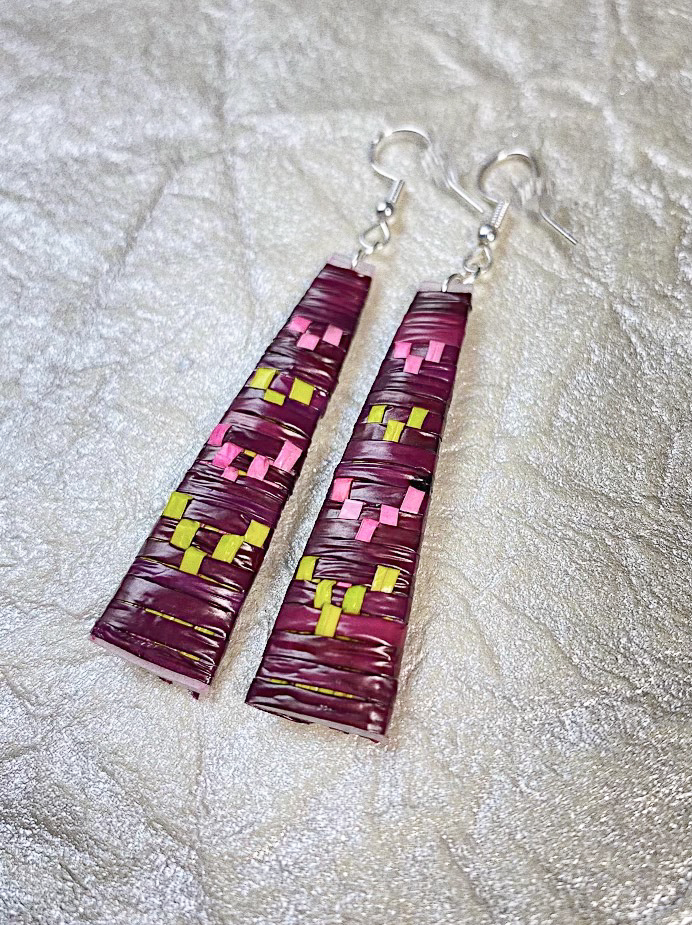 A pair of deep purple earrings with bright green and pink motifs.