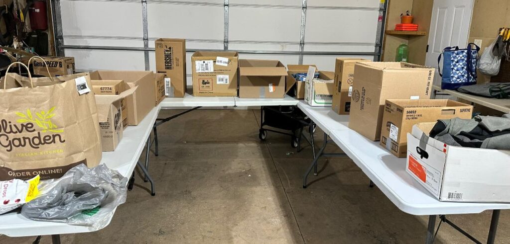 A dozen cardboard boxes of various sizes sitting on several folding tables.