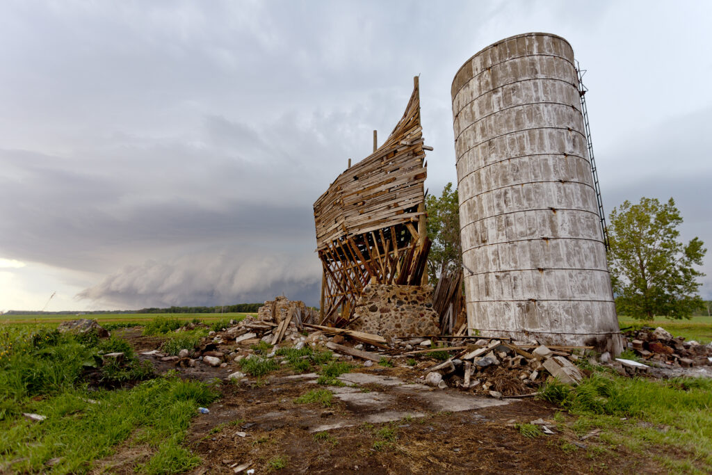 A silo and a large wooden structure resembling a ship standing in a field.