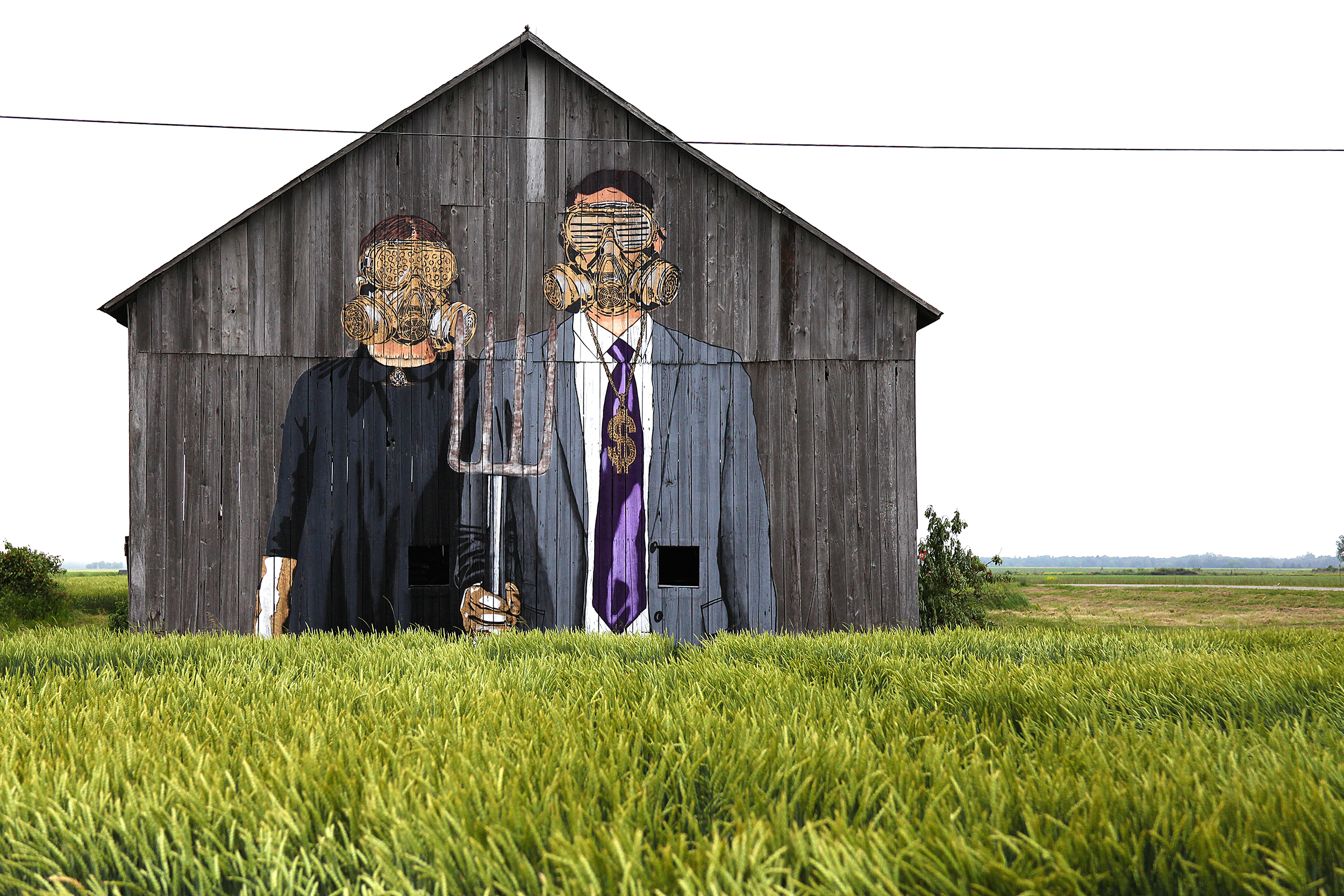 An old grey barn with a mural painting depicting two people in gas marks. One is holding a pitchfork.