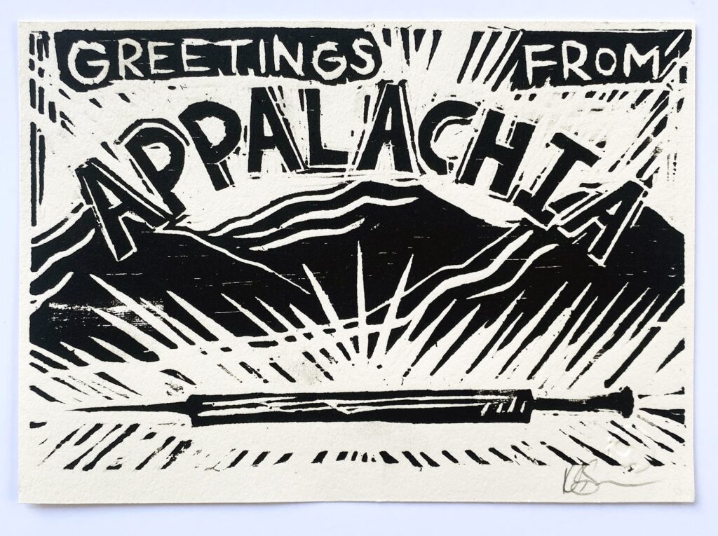 A black and white print depicting a mountain landscape with a large needle in the foreground. It is shaped like a postcard and the text reads "Greetings From Appalachia."