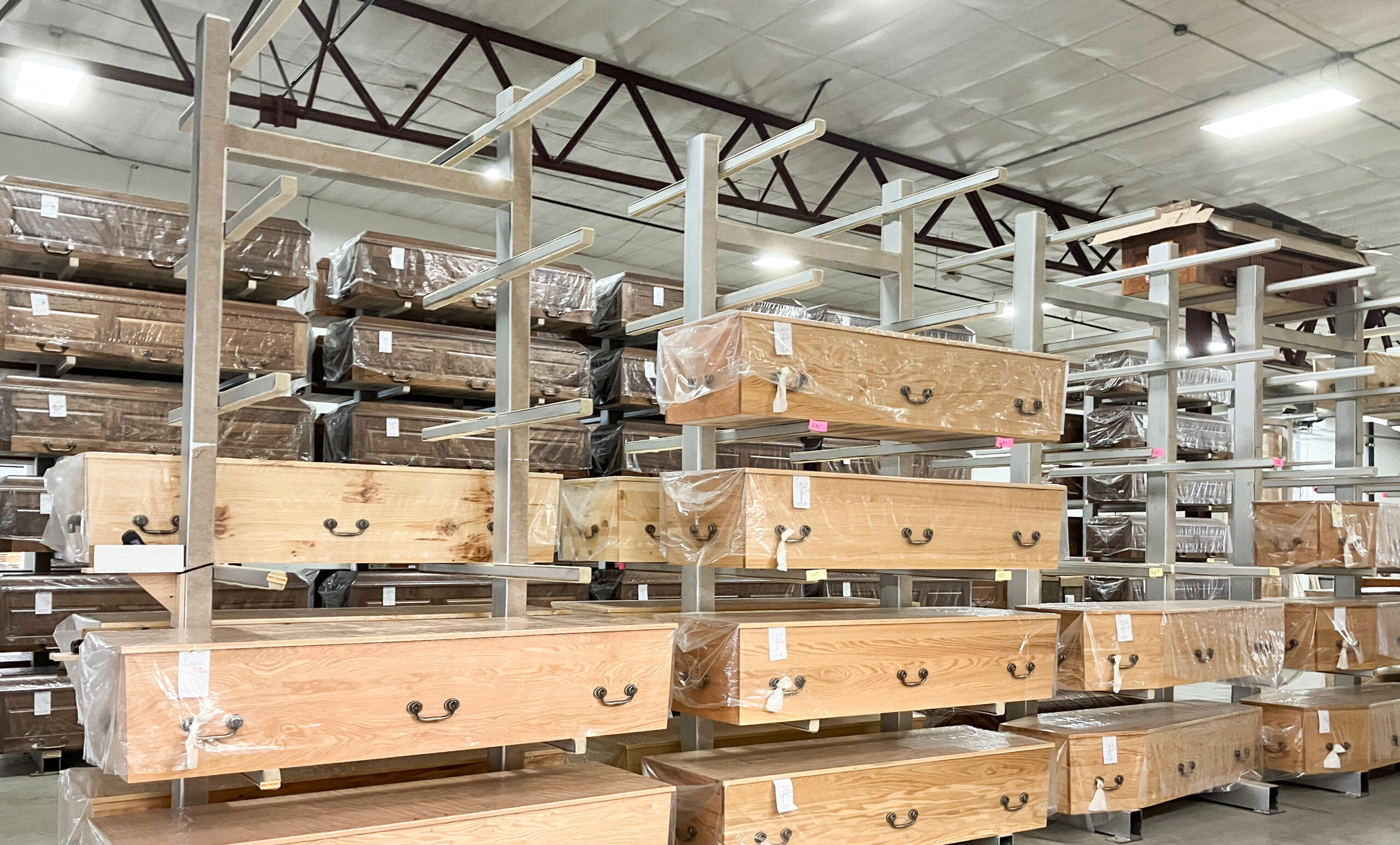 A large warehouse with shelving with different kinds of wooden caskets.