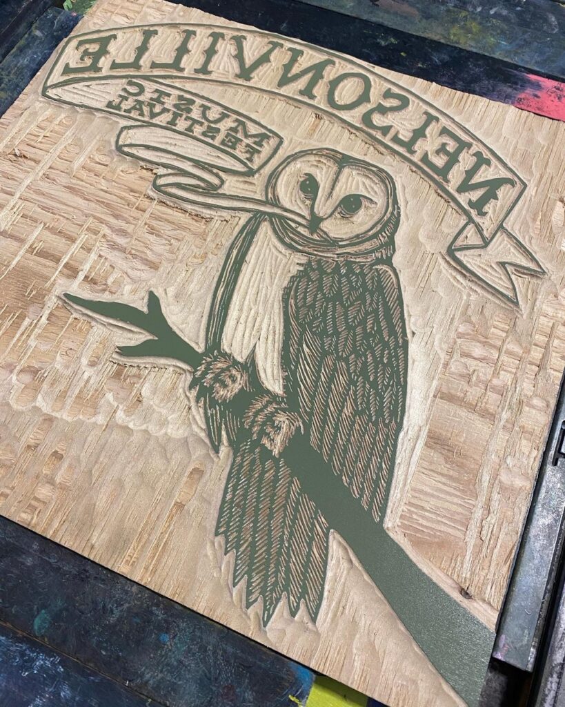 A carved woodblock depicting an owl sitting on a branch.