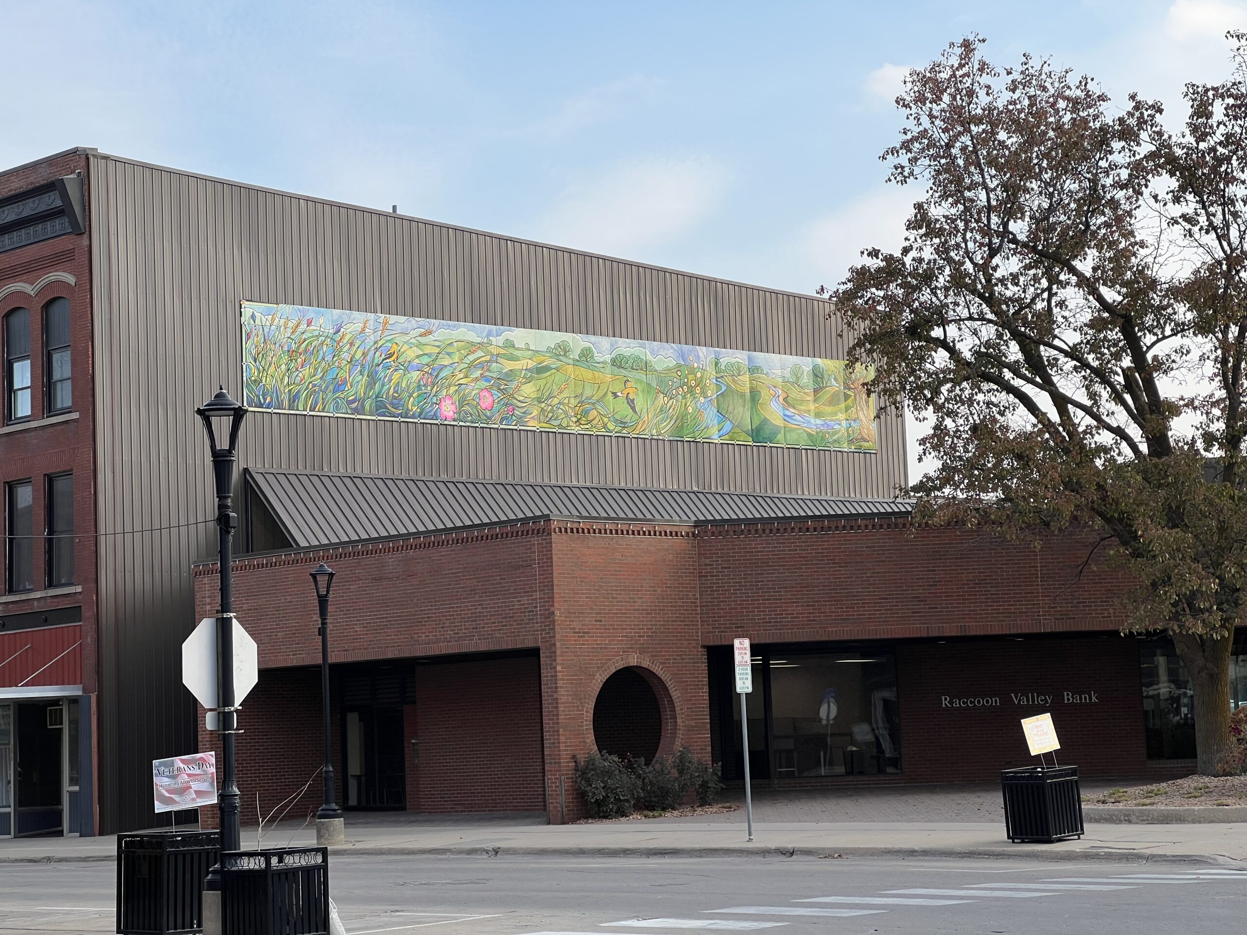 A lush green mural showing prairie life on the side of a mainstreet brick building