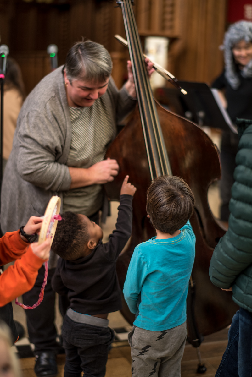 Children point to bass instrument held by musician.