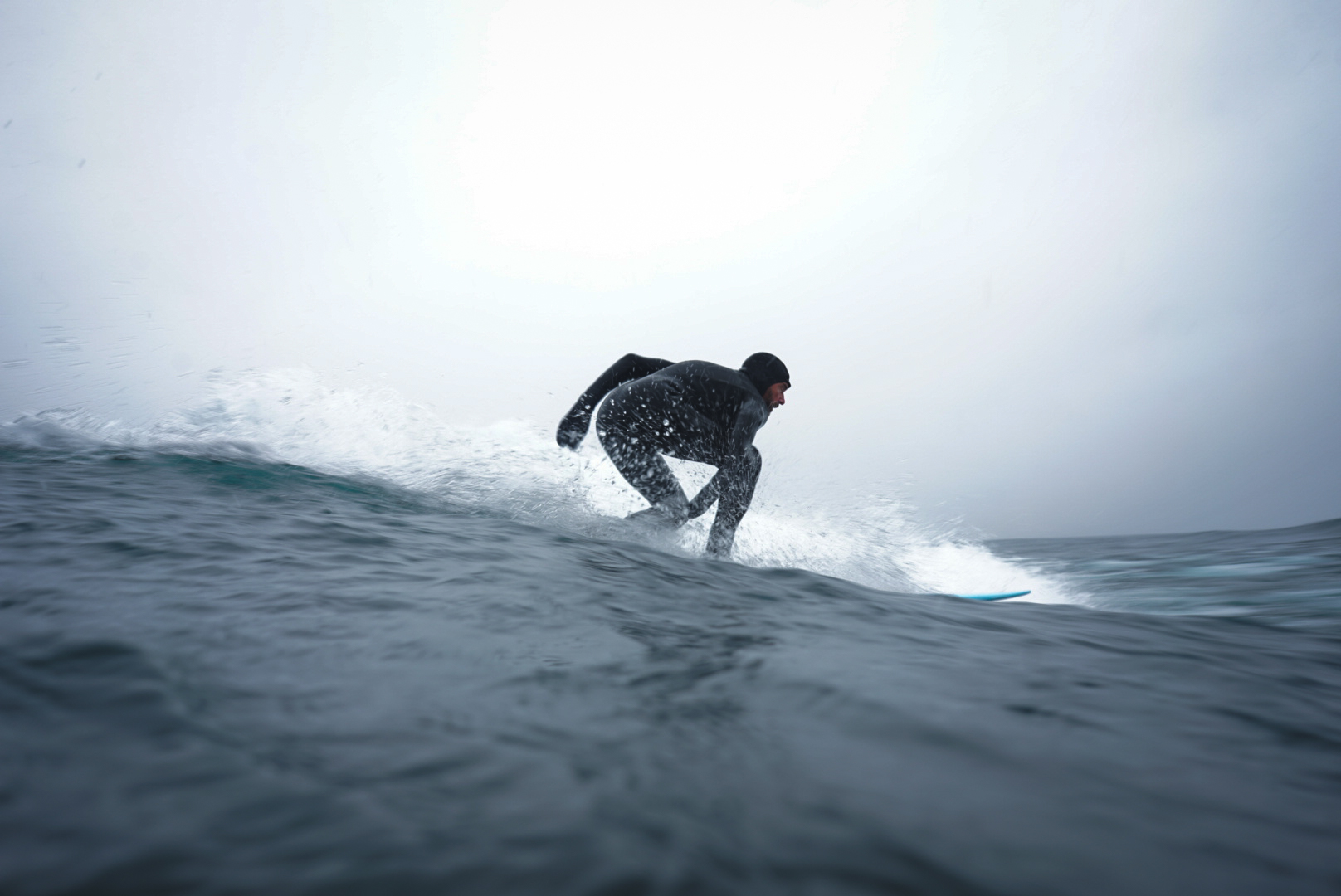 A surfer wearing a full wet suit catching a wave.