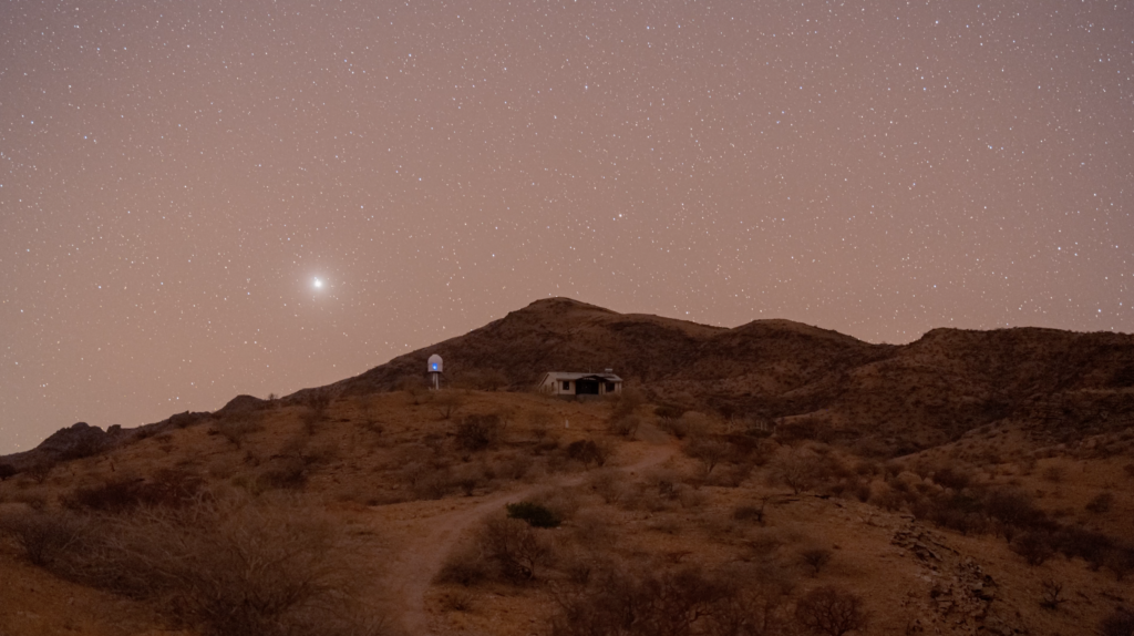 A night scene of a house on a hill surrounded by stars