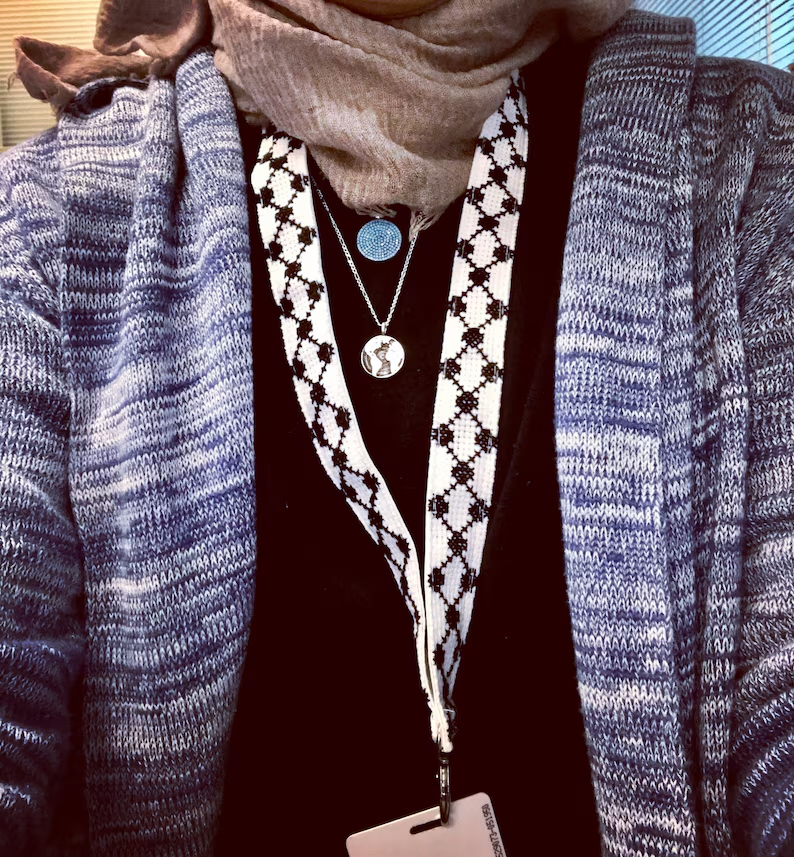 A person with an embroidered black and white lanyard hanging down from their neck.
