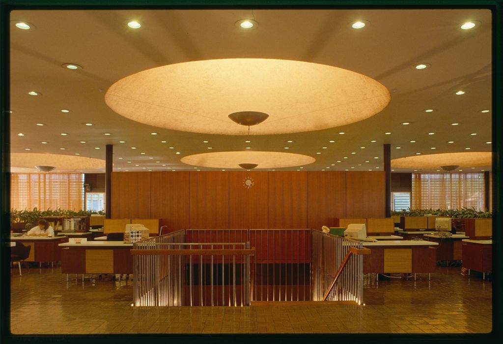 An office space with large recessed circular architectural lighting features. The ceiling is also dotted with rows of small lights.