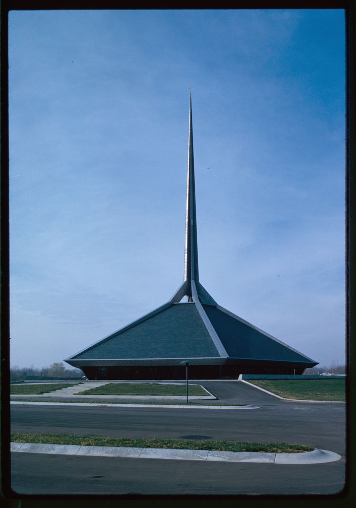 A building with a district angular architectural shape and a tall needle-like feature emerging from its center.