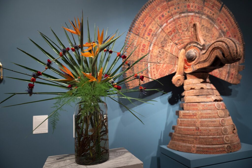 A traditional Latin American sculpture paired with a colorful and spiky floral arrangement