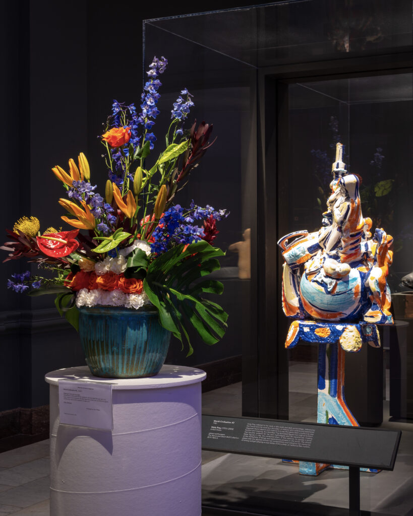 A colorful statue paired with a flamboyant floral arrangement