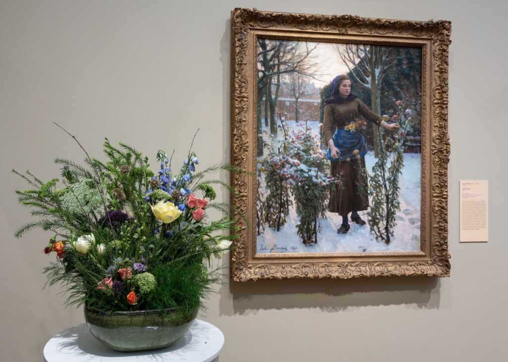 A painting of a woman in the snow with with flowers and a floral arrangement