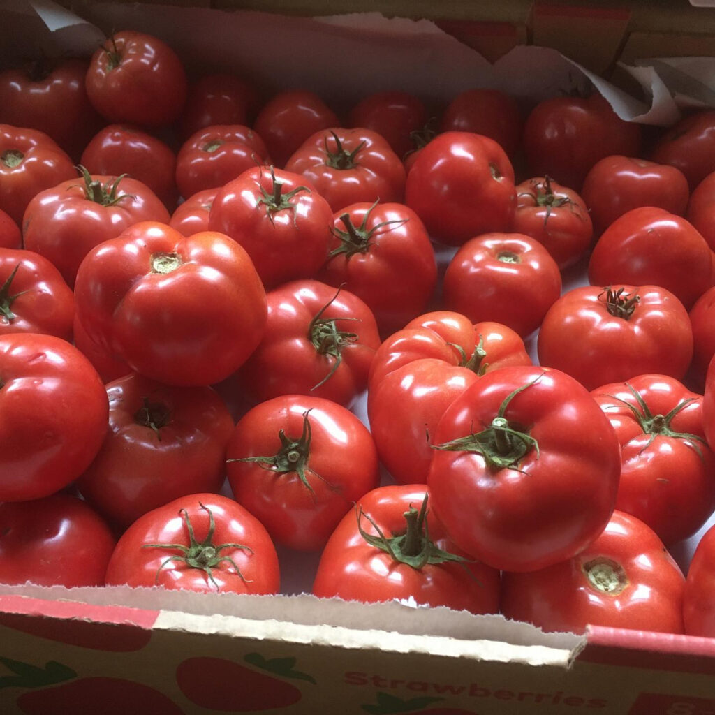 A cardboard box full of bright red tomatoes.