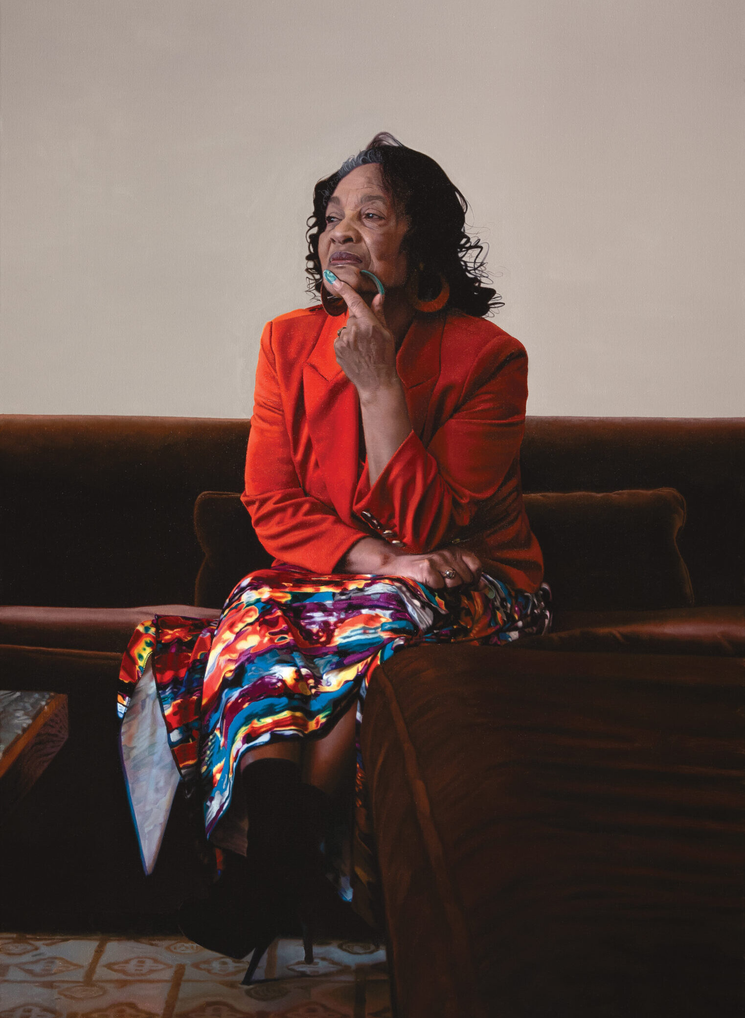 A painting of an older person wearing a bright red jacket and patterned skirt, sitting on a couch. They have bright blue nails and have one of their hands resting by their chin.