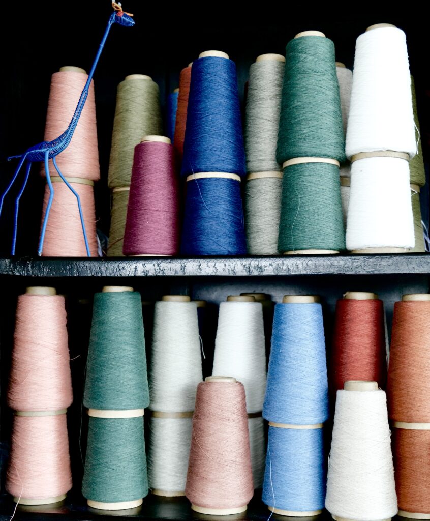 Spools of thread in different colors stacked on a shelf.