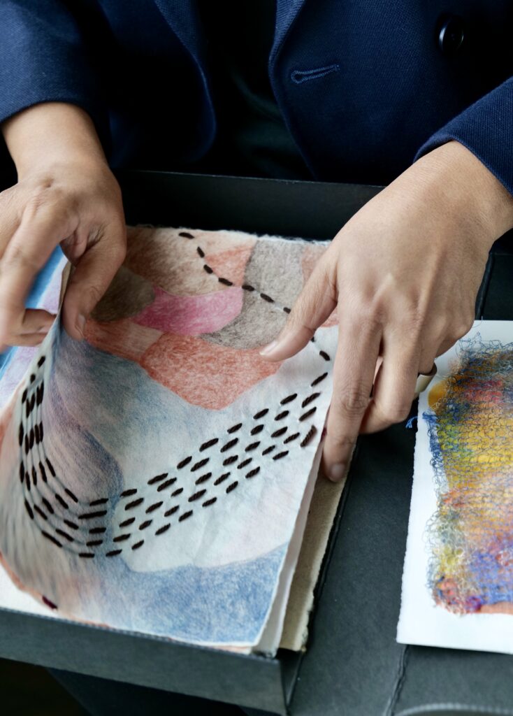 A person's hands sift through artworks made on paper.
