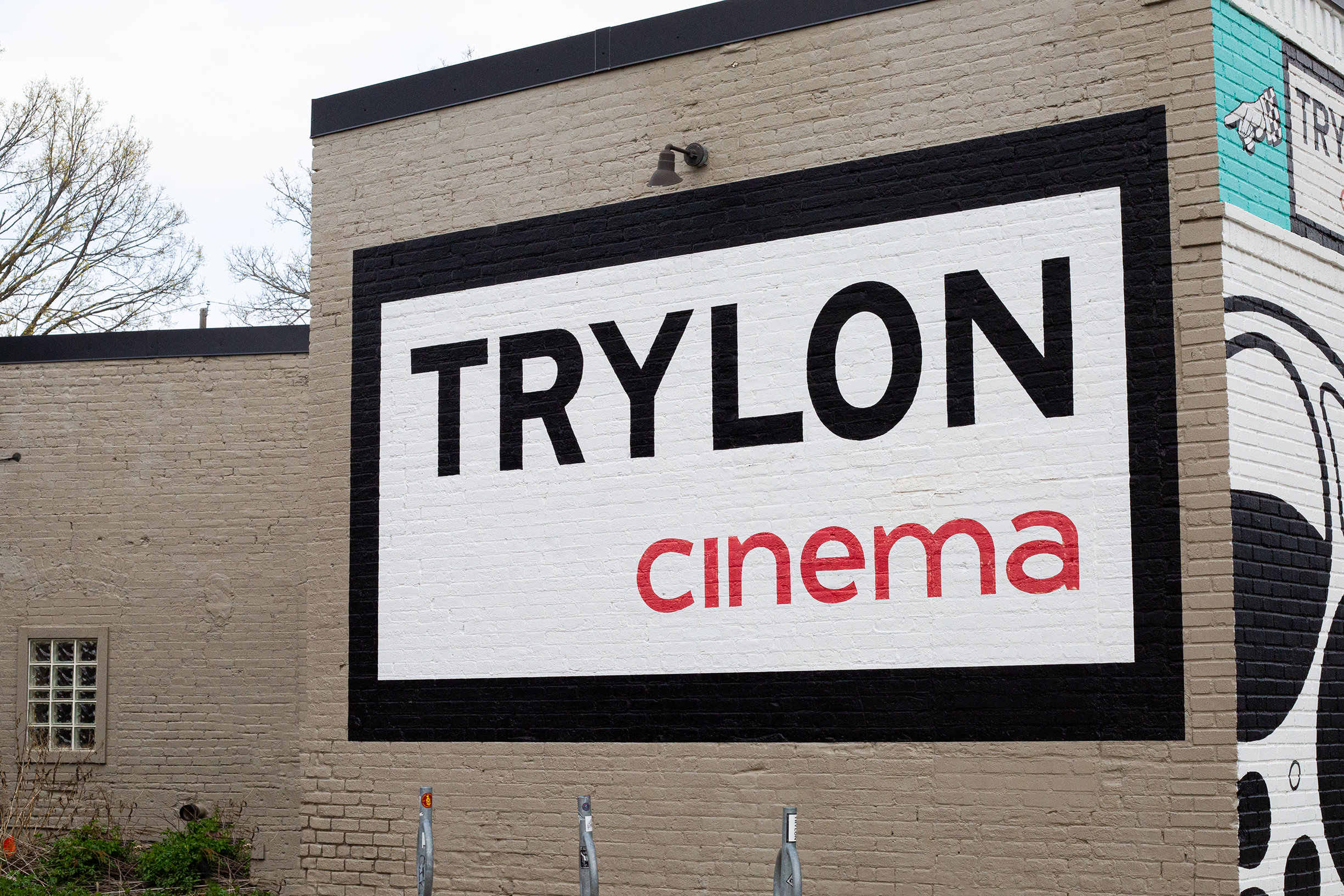 A mural reading, "Trylon Cinema" painted on the outside of a building.