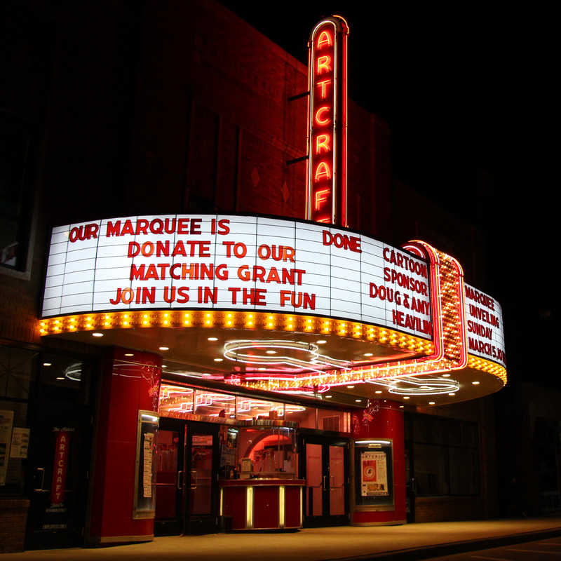 A theater building at night with bright red and yellow lights and signage reading "Artcraft".