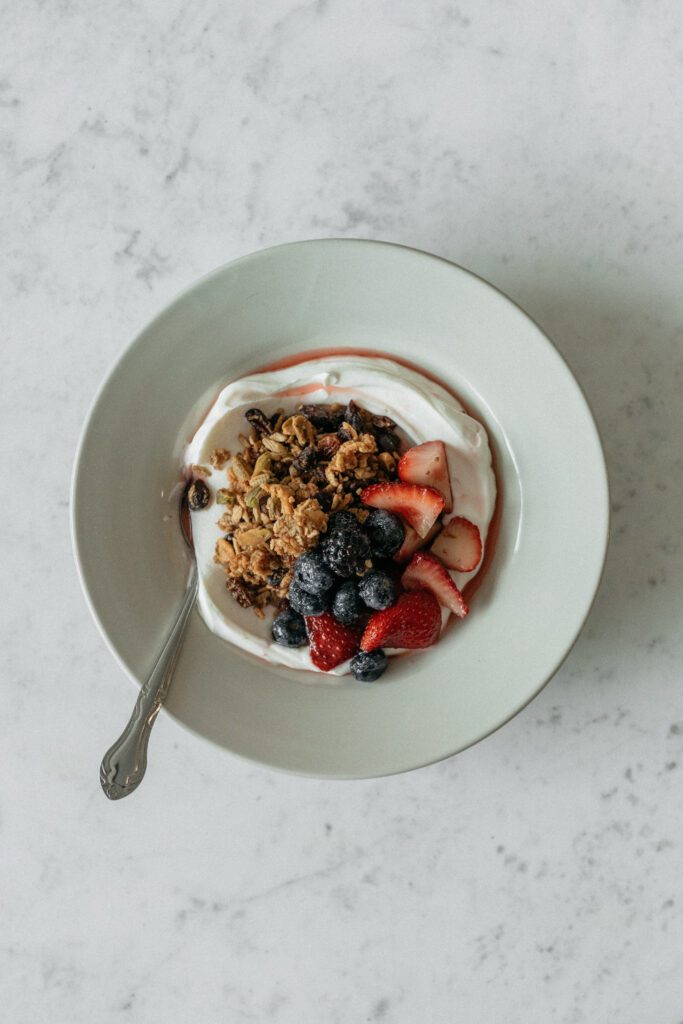 A bowl of yogurt, granola, and fruit photographed from above.