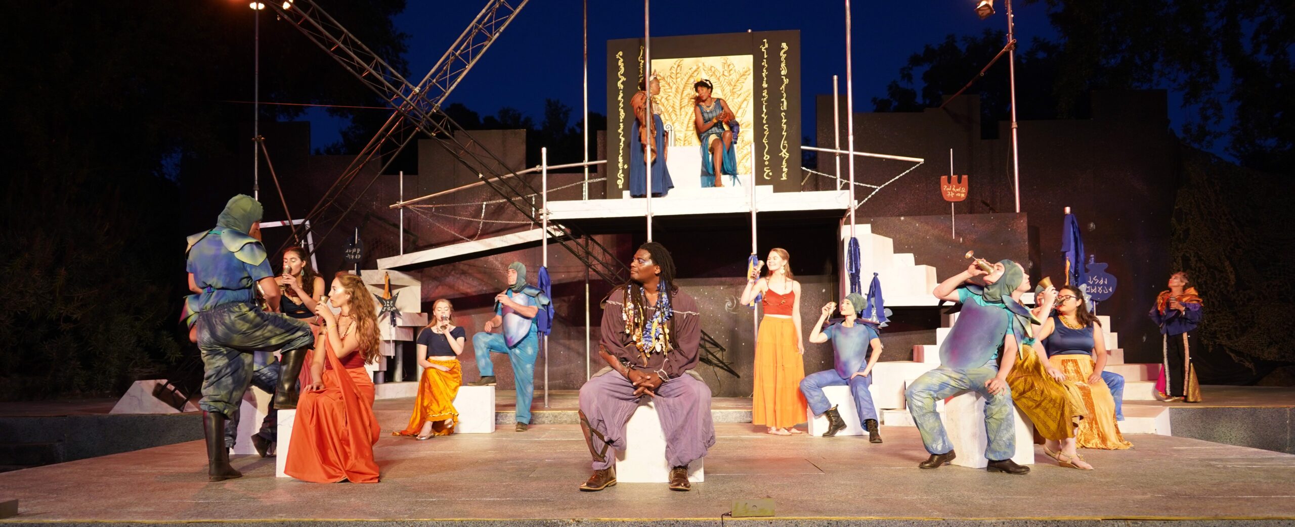 A stage full of actors dressed in Ancient Greek-inspired outfits.