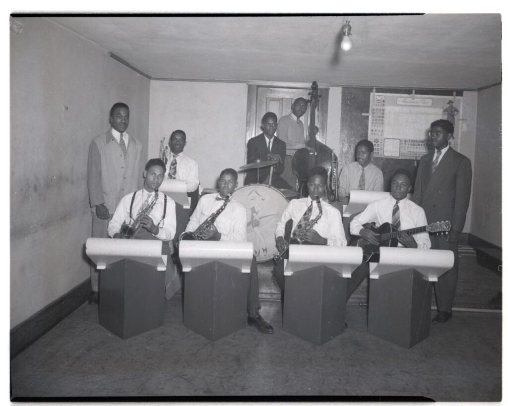 An archival black and white photo of an all-Black band with musicians playing different instruments.