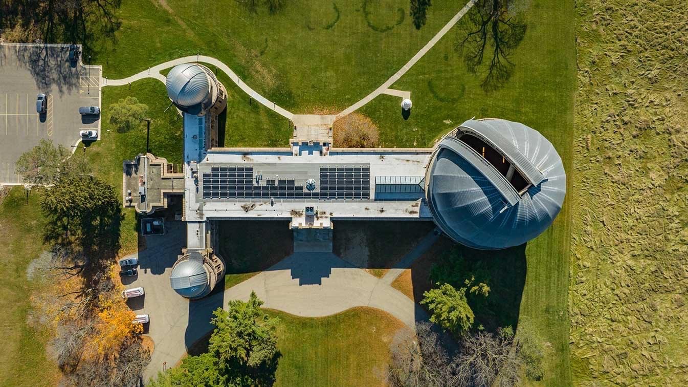 An aerial view of an observatory building with one large dome at one end and two smaller ones at the other.