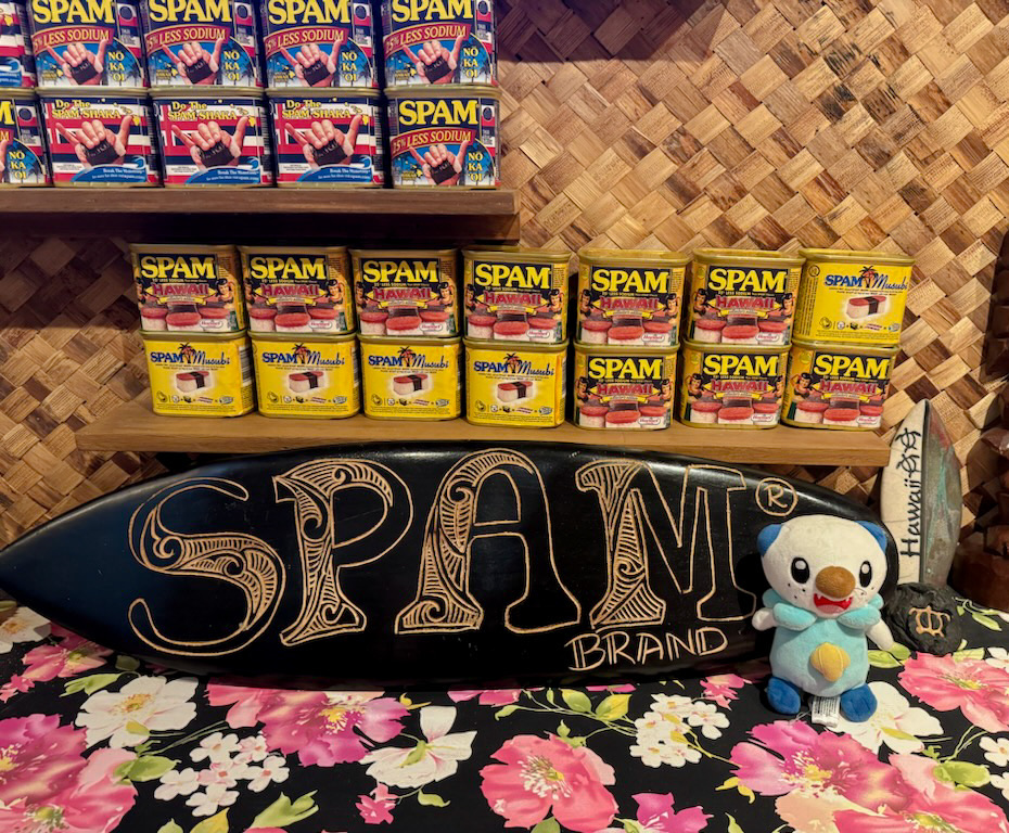 A small display with several cans of Hawaiian SPAM, with a miniature surfboard engraved with the words, "SPAM brand"