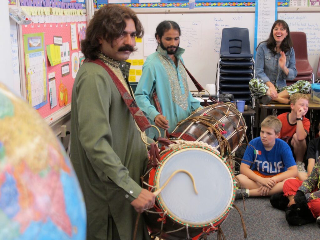 Two men in Pakistani garb and drums in an American classroom