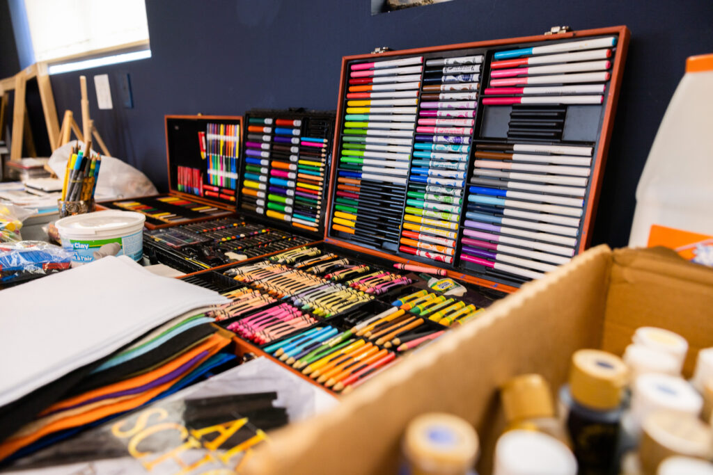 A table full of art supplies including markers, crayons, color pencils neatly organized in a case.