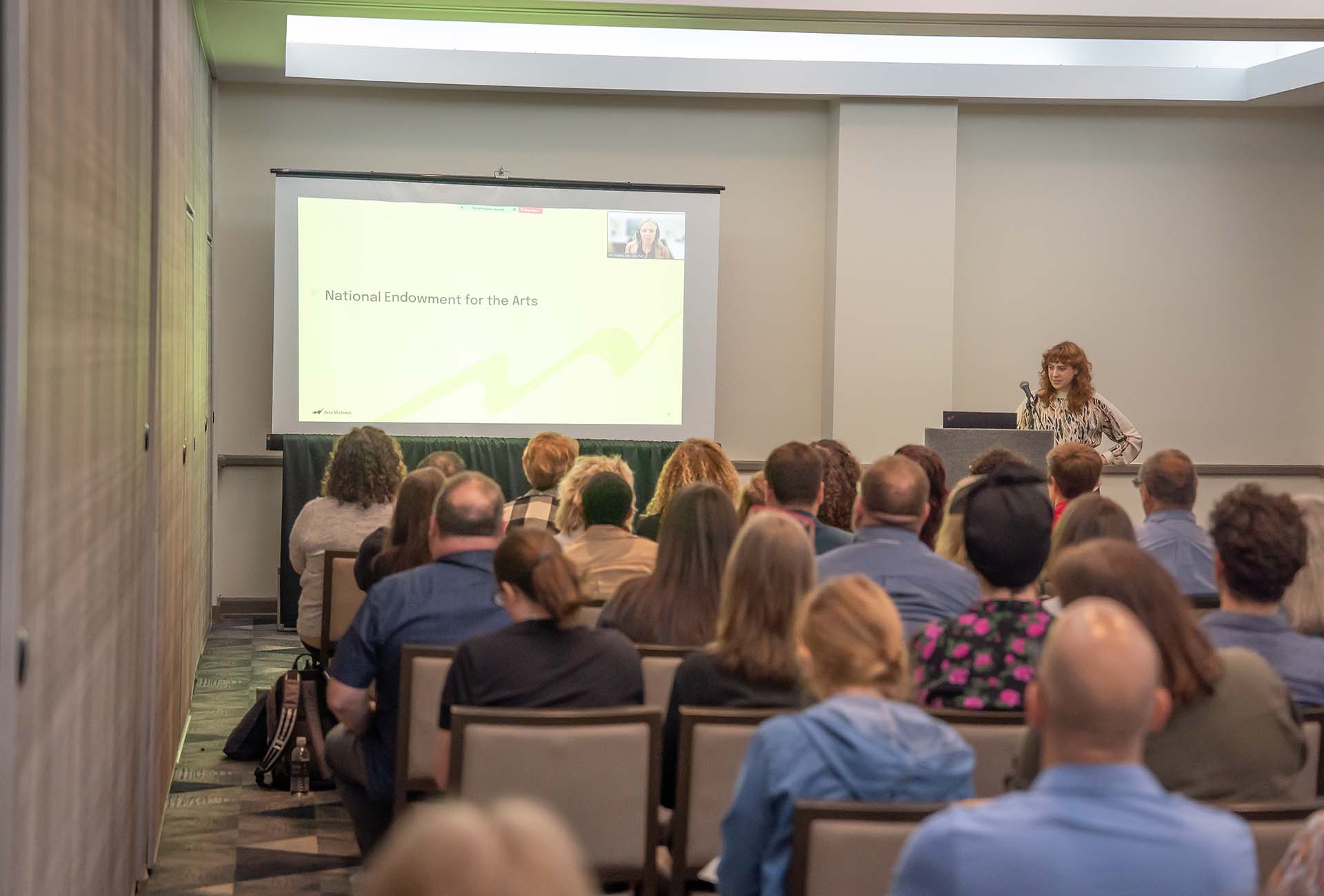 A conference room filled with attendees listening to a presentation from the National Endowment for the Arts