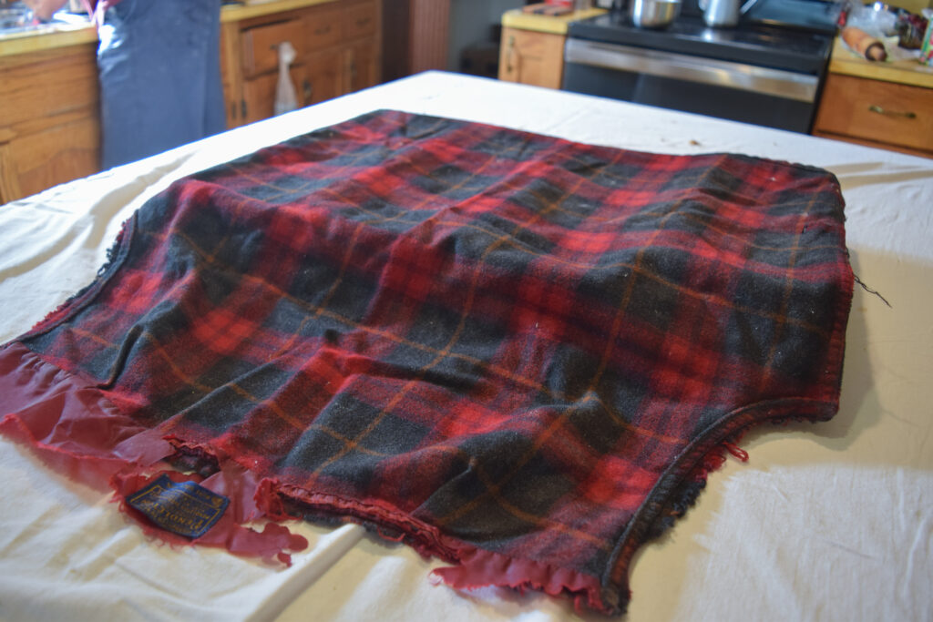 A red and black plaid fabric on a table covered in a white sheet.