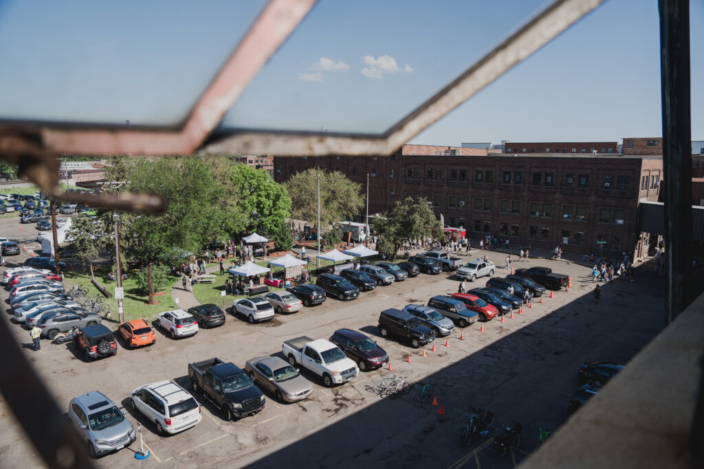 A view of a parking lot from a higher vantage point. The lot has brick building surrounding it.