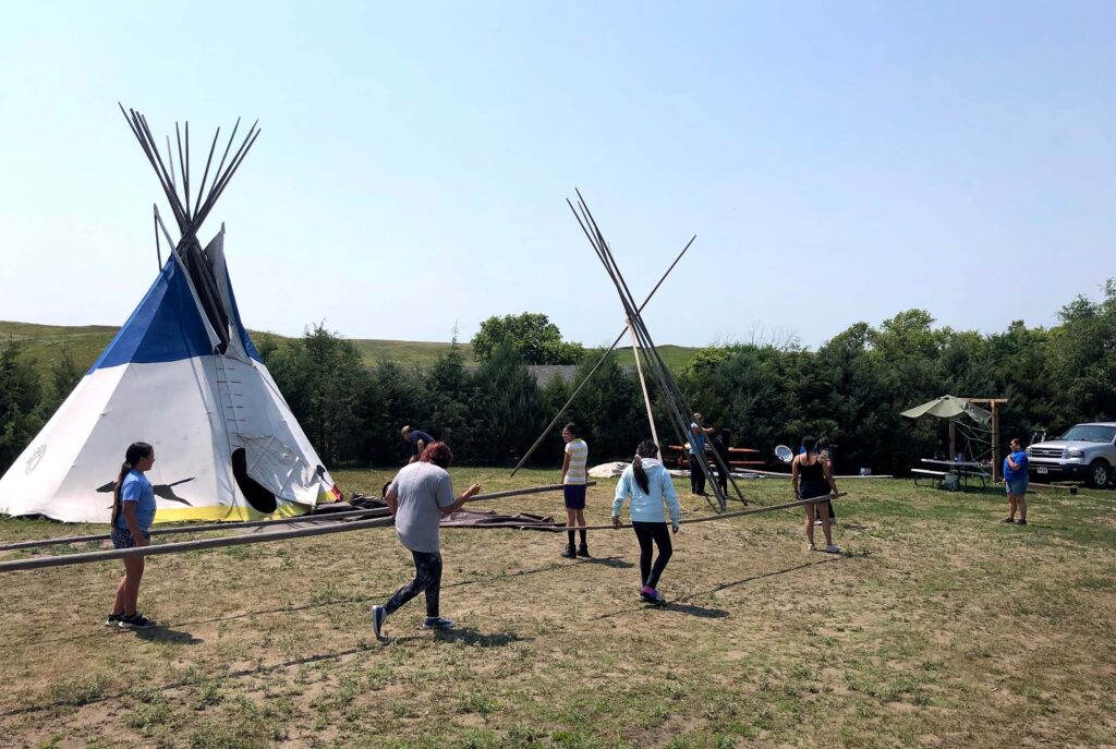 A group of youth building a tipi frame.