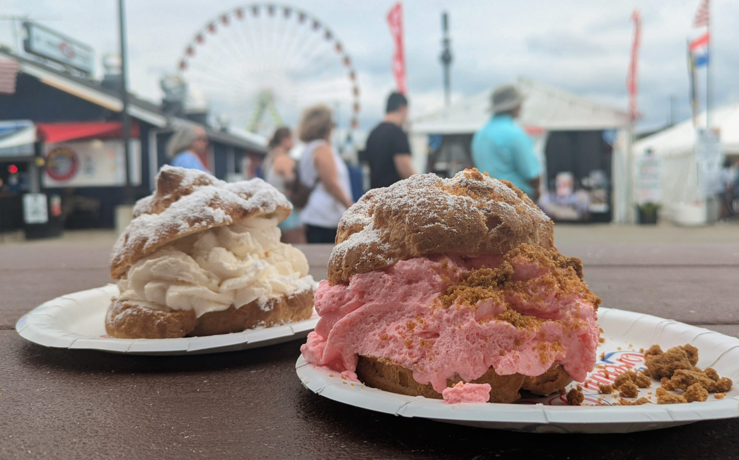 Two brown baked pastries, sliced in the middle. One has white colored filling, while the other has a pink filling with a dusting of brown.