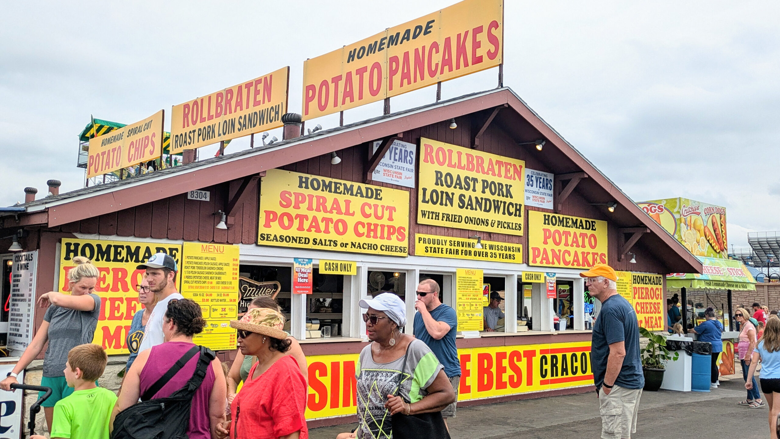 A building with various large signs on the exterior. The signages have words written in bold red, black text. One of them reads, "Rollbraten roast pork loin sandwich with fried onions and pickles" and another sign reads "homemade potato pancakes"