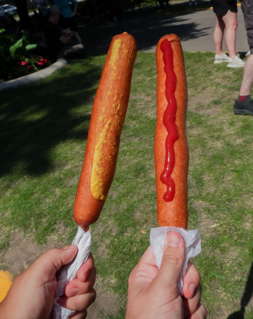 Two foot-long corn dogs, one with mustard and one with ketchup.