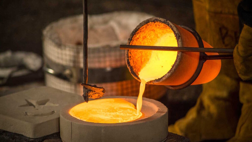 A pot pouring red-hot molten metal into a stone mold.