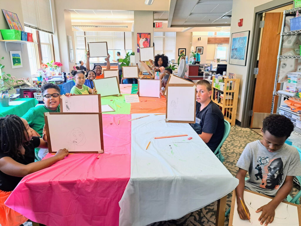 A group of children show off their drawings in a colorful space.