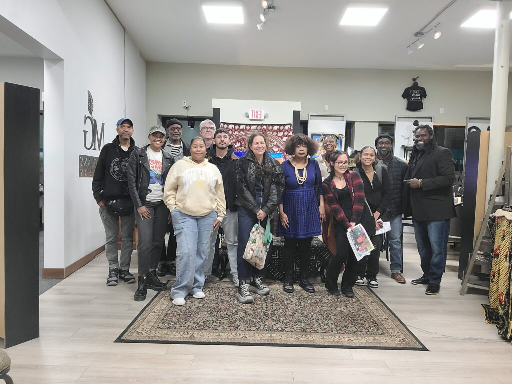 A group of twelve people of different ages and races pose for the camera.