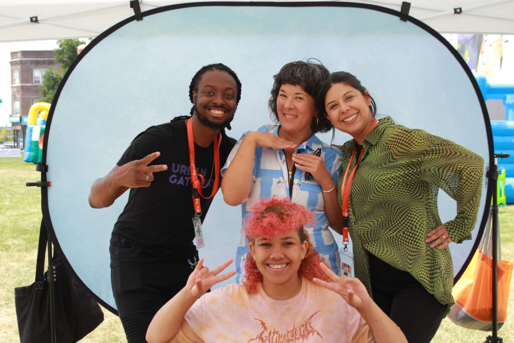 Four people of varied ages and races pose for the camera in front of a pop up photo background.