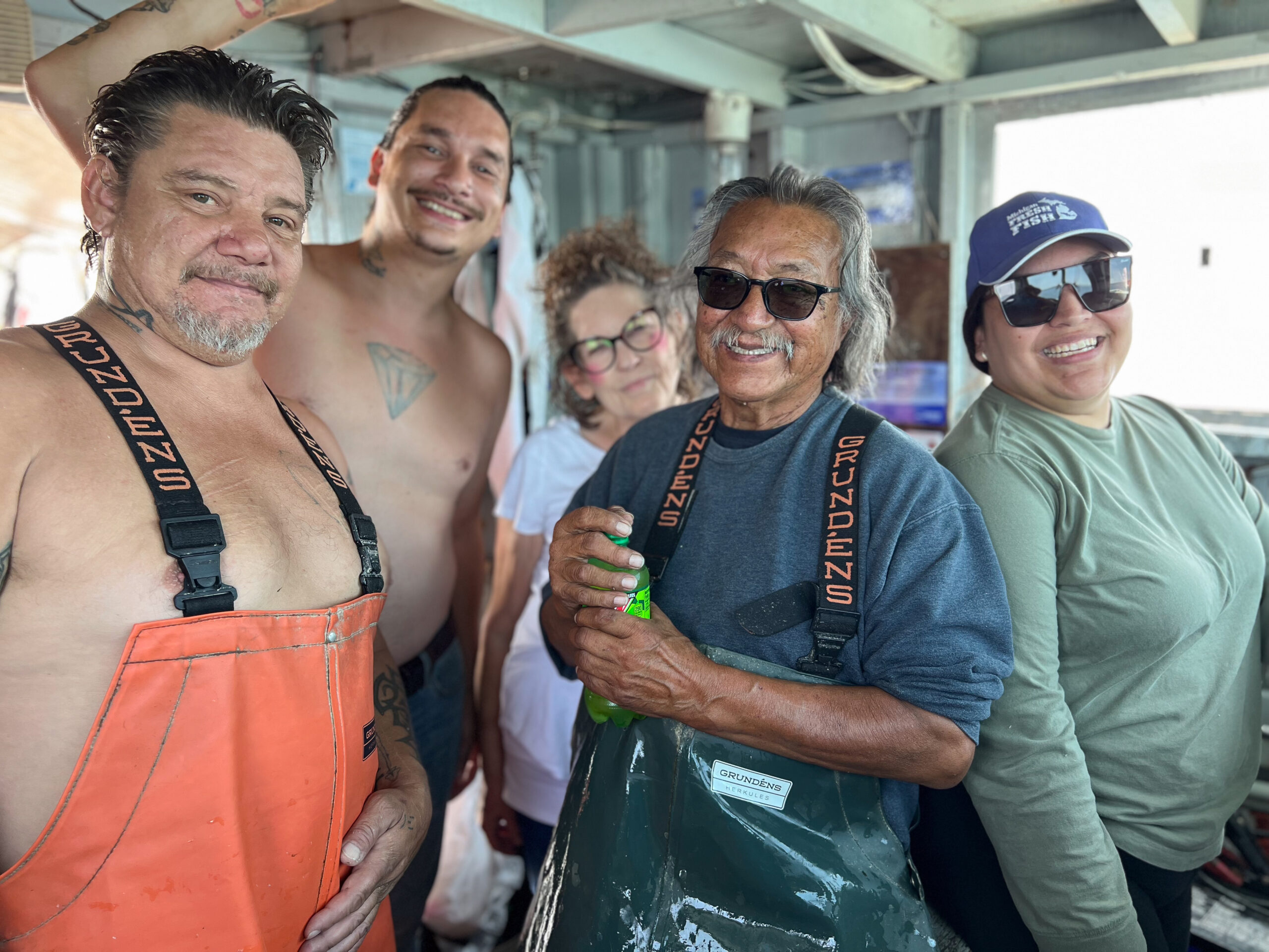 Five crew members posing in a boat cabin.