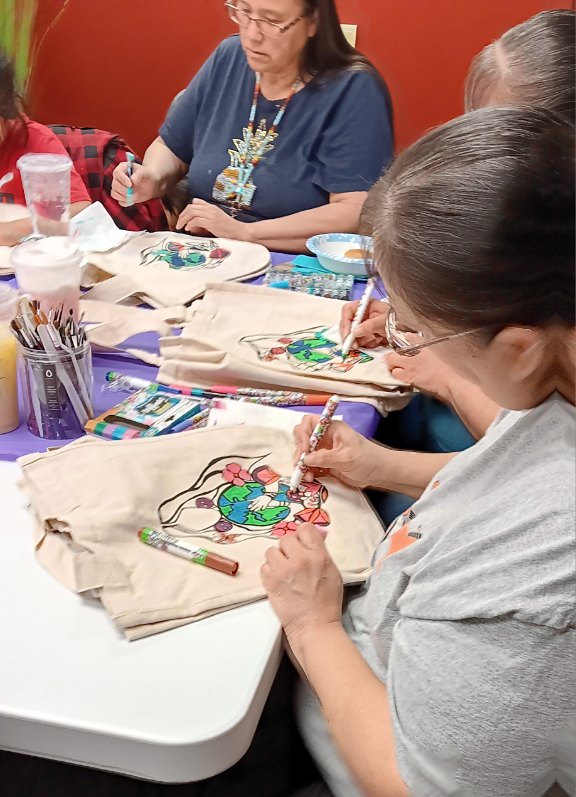 A group of Native artists paint on eco-bags with markers