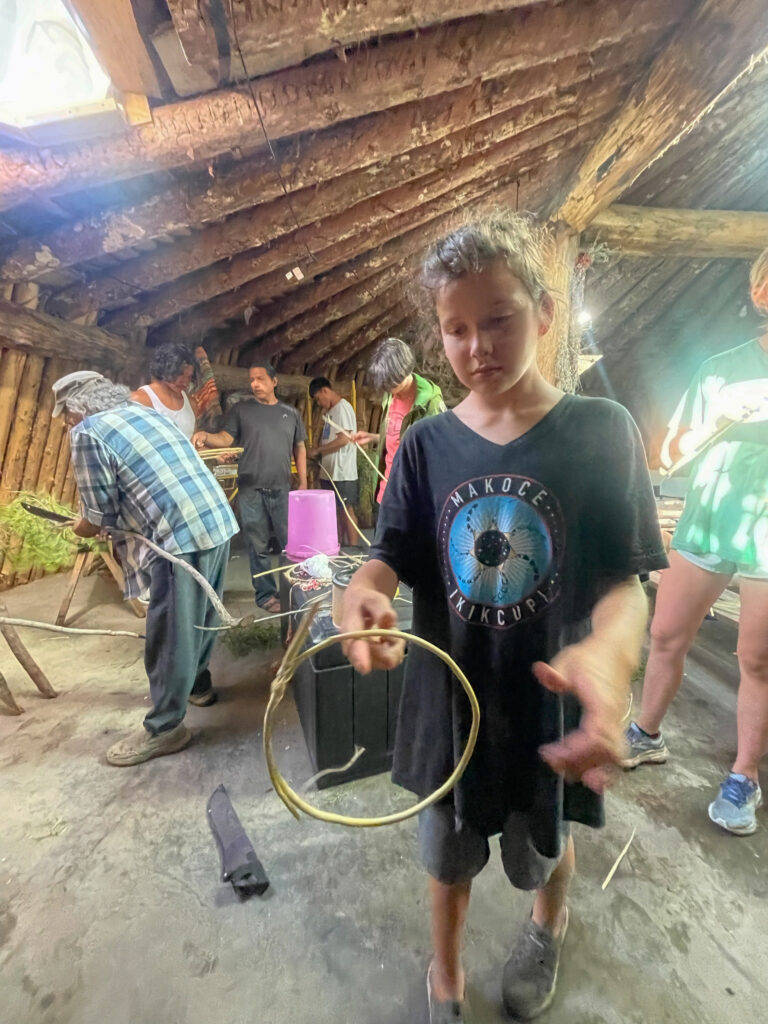 A child holds a wooden hoop in their hand.