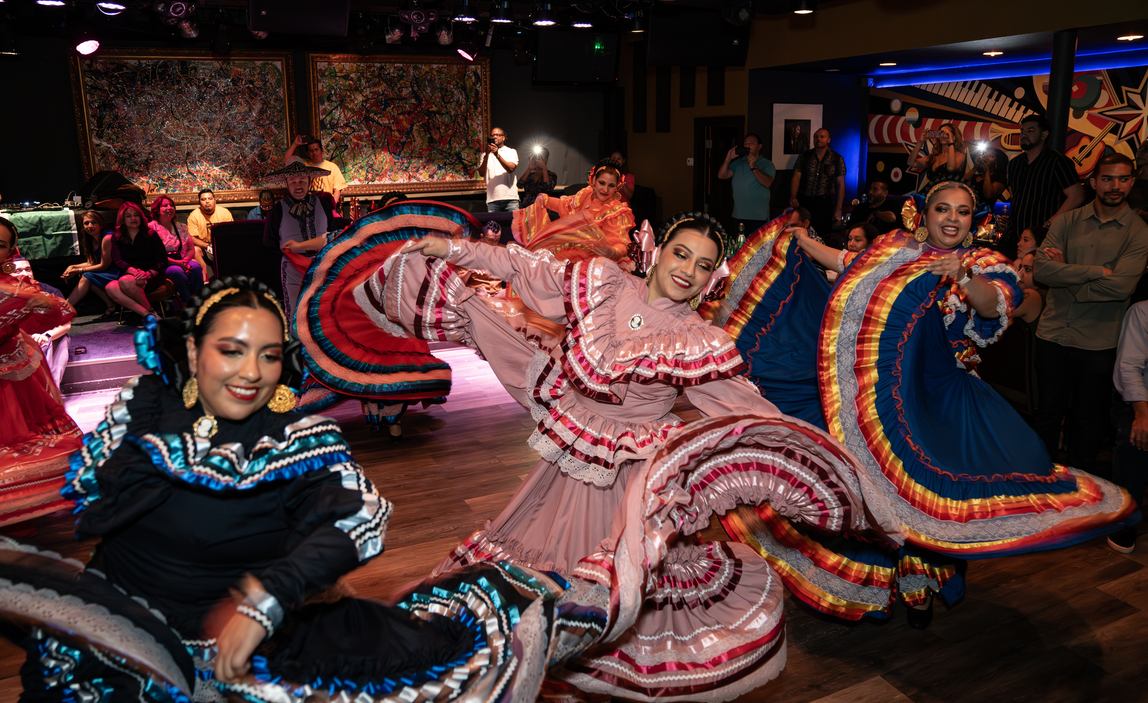 Dancers in colorful, traditional dresses performing, as a crowd looks on.