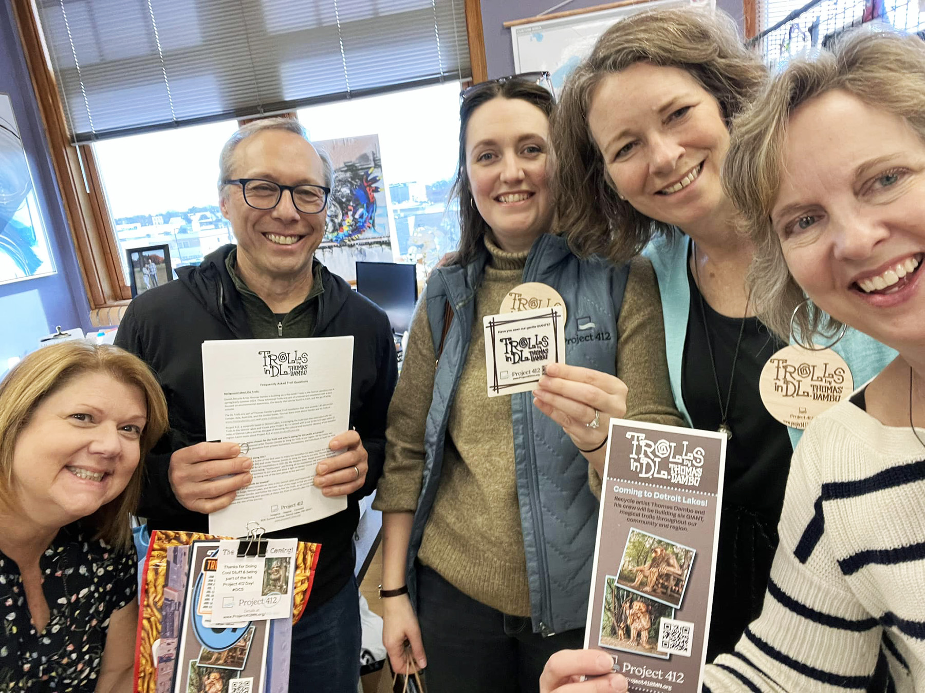 A group of five people with light skin tone holding up fliers and stickers that read Trolls in DL